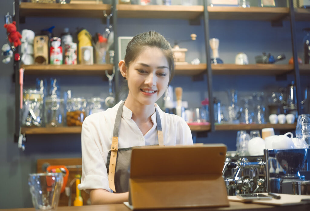 Attractive Young Woman Barista Of Her Trendy Cafe Working Online